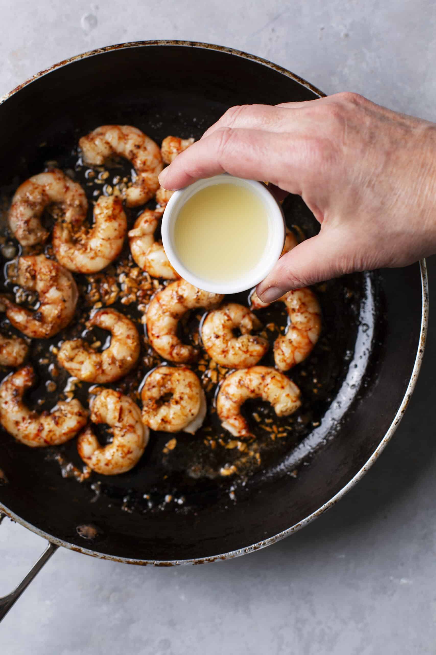 Juicy shrimp being cooked in a skillet with garlic and spices.