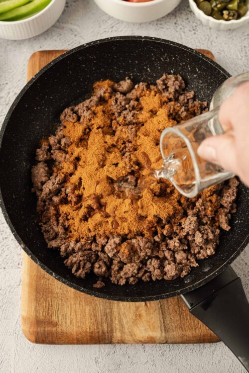 Ground beef with spices cooking in a skillet, adding flavor for a savory dish.