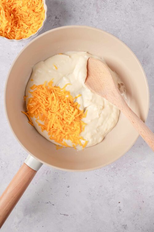 Cream cheese, shredded cheddar cheese, and sour cream in a mixing bowl for cheesy dip recipe.
