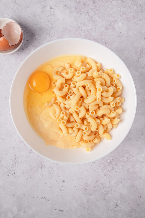 Soft boiled eggs and uncooked pasta in a white bowl for easy cooking.