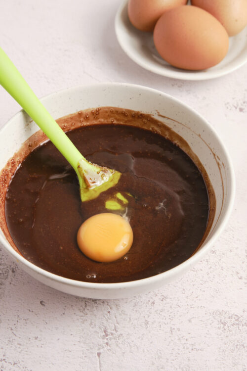 Creamy chocolate cake batter with egg in mixing bowl, ready for baking.