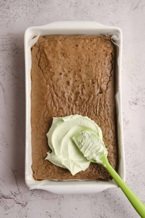 Cream cheese frosting spreading on baked chocolate sheet cake.