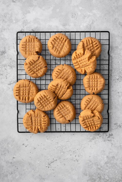 Fresh peanut butter cookies with classic lattice pattern cooling on a wire rack.