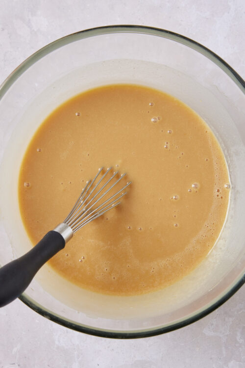Smooth caramel sauce in a glass bowl with a whisk for baking recipes.