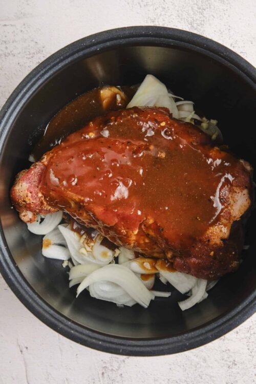 Succulent pork shoulder with barbecue sauce in a slow cooker, ready to cook.