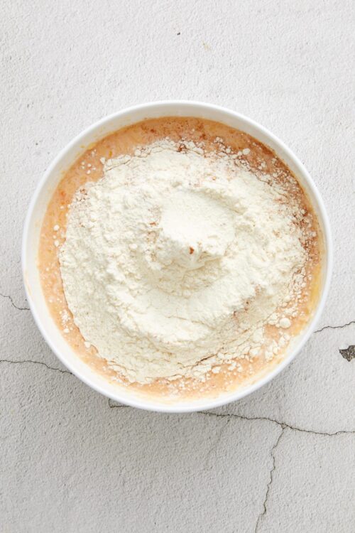 Flour being added to a mixing bowl for baking recipe at Baked Bree.