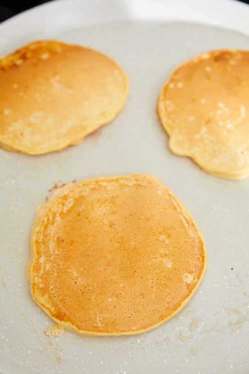 Fluffy pancake batter cooking on a griddle, perfect for breakfast or brunch.