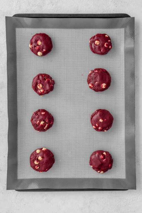 Fresh raspberry white chocolate cookie dough balls on baking sheet.