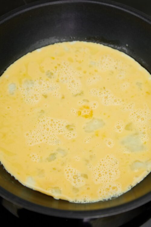 Fluffy scrambled eggs cooking in a black skillet.