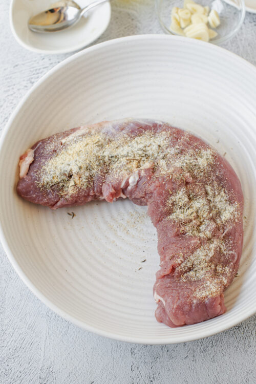 Juicy raw pork loin seasoned with herbs and spices ready for cooking.
