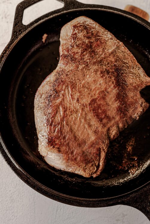 Juicy roasted beef brisket cooking in a cast iron skillet.