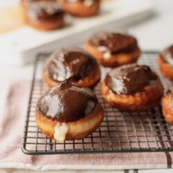 Rich chocolate-glazed donut holes on cooling rack for dessert or breakfast.