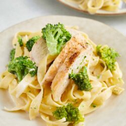 Creamy chicken fettuccine with broccoli on a white plate, homemade pasta dish, comforting Italian meal.
