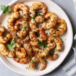 Succulent grilled shrimp with herbs on a white serving plate.