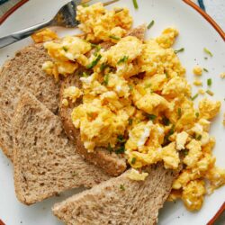 Scrambled eggs with toast on a white plate, fresh and homemade breakfast idea.