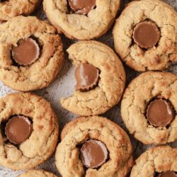 Butter cookies with chocolate centers arranged on a textured surface.