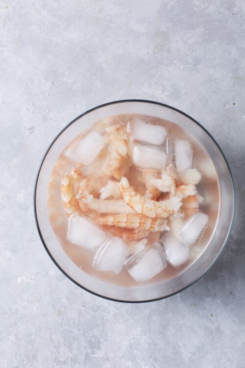 Juicy cooked shrimp with ice cubes in a glass bowl, concept for seafood and shrimp recipes.