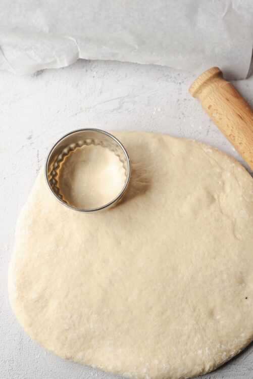 Flour dough with cookie cutter on baking sheet for baking.