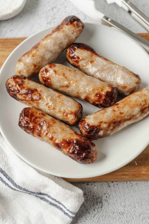 Succulent homemade sausages with crispy, caramelized exterior on a white plate.