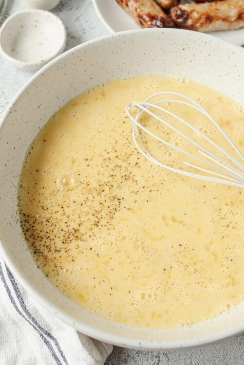 Butter mixture with black pepper and whisk in a white bowl.