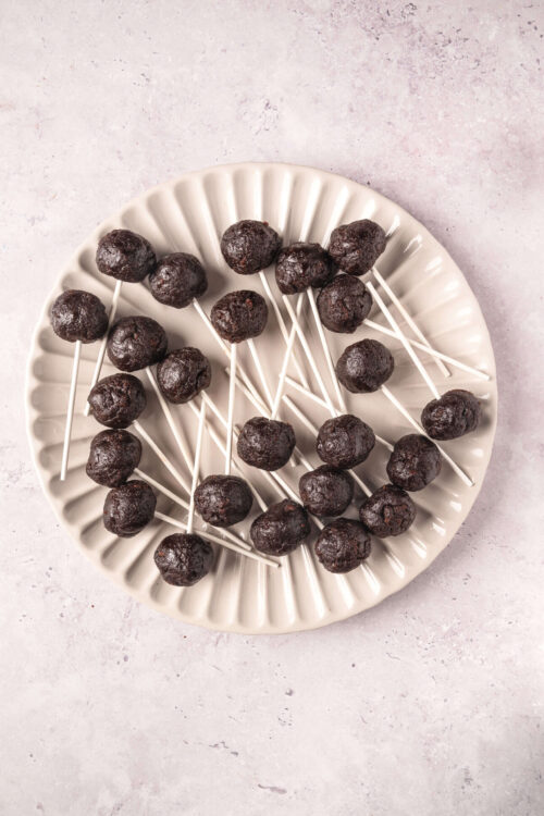 Decadent chocolate cake pops on a white ceramic plate, perfect for dessert or party treats.