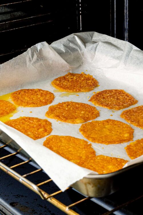 Golden baked peanut butter cookies cooling on parchment paper in the oven.