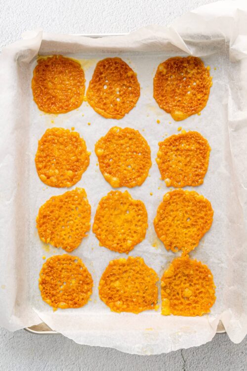 Crispy cheesy baked cheese crisps on parchment paper, ready to serve as snacks or appetizers.