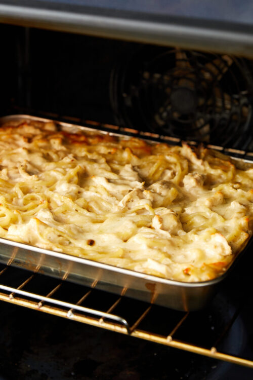 Golden baked casserole with cheese and chicken in oven, homemade comfort food.