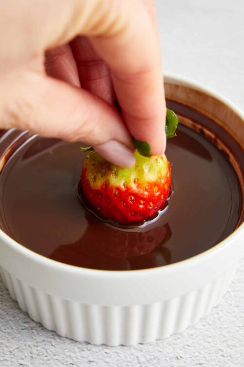 Fresh strawberry being dipped into chocolate fondue for a delicious dessert.