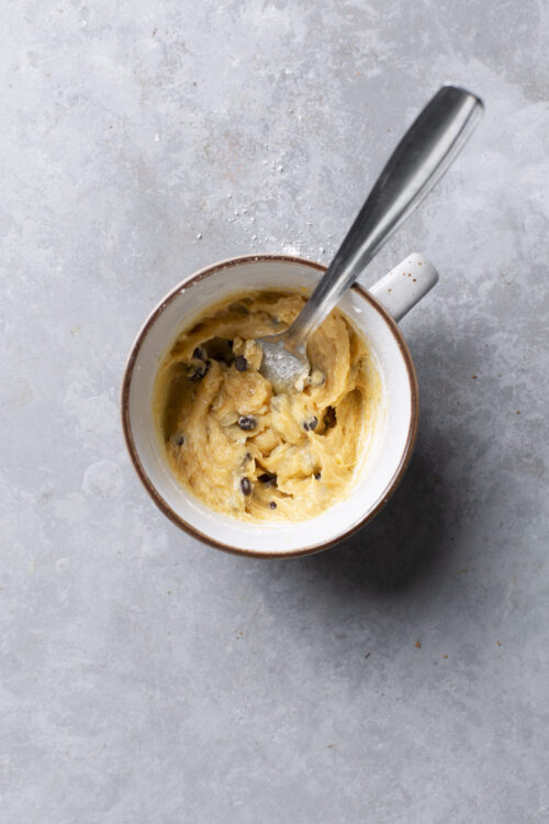 Creamy cookie dough ice cream in a mug with a spoon, ready to serve.