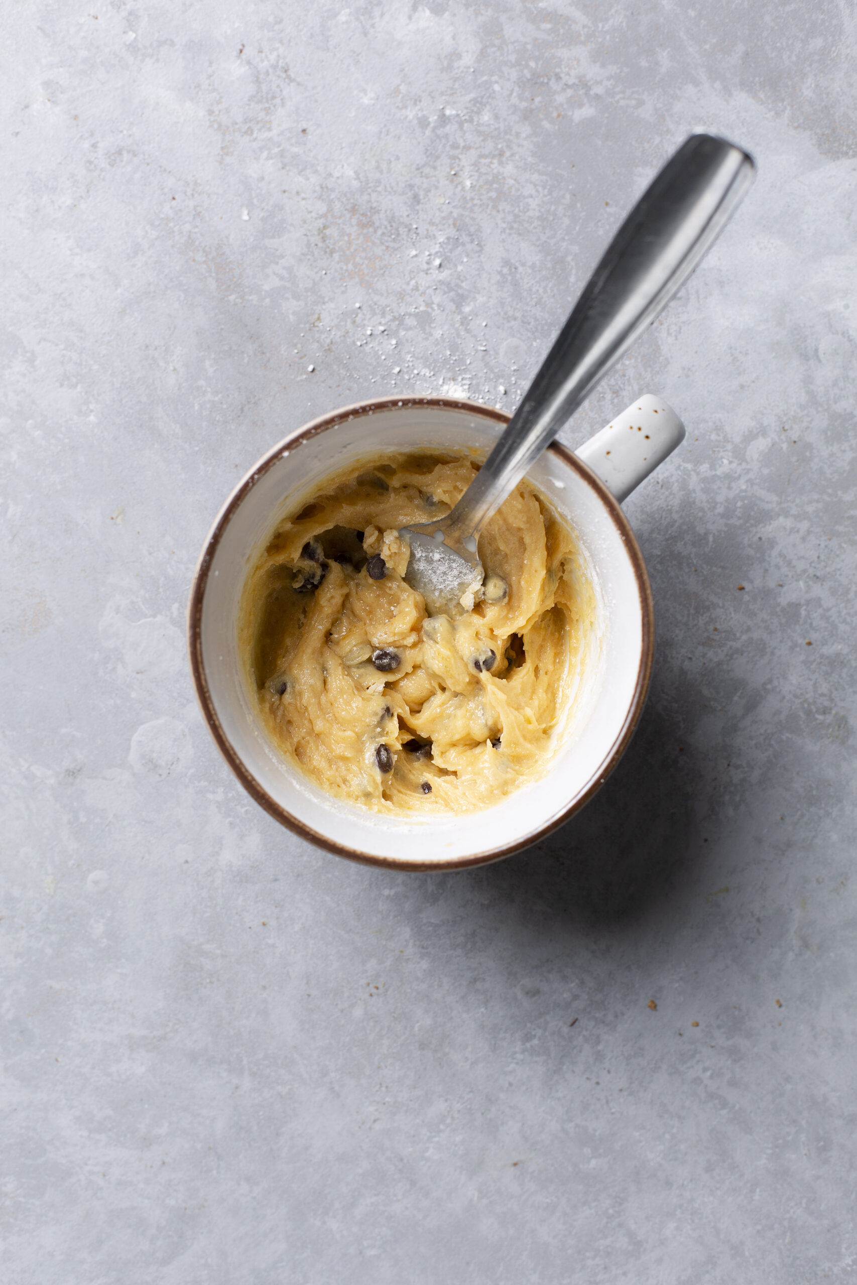Creamy cookie dough ice cream in a mug with a spoon, ready to serve.