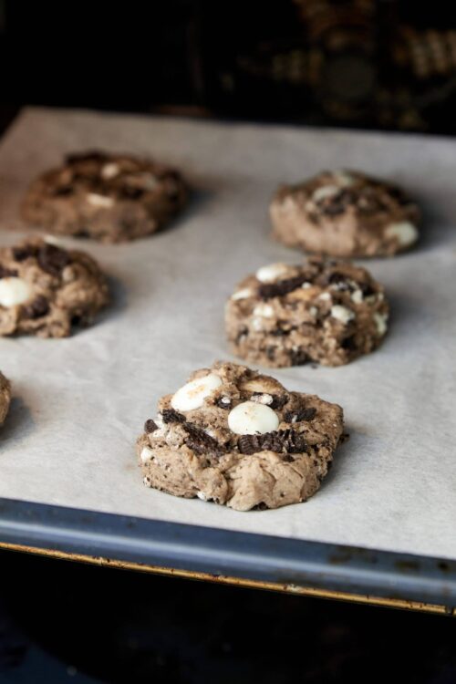 Chewy chocolate chip cookies with white chocolate chunks cooling on a parchment-lined baking sheet.