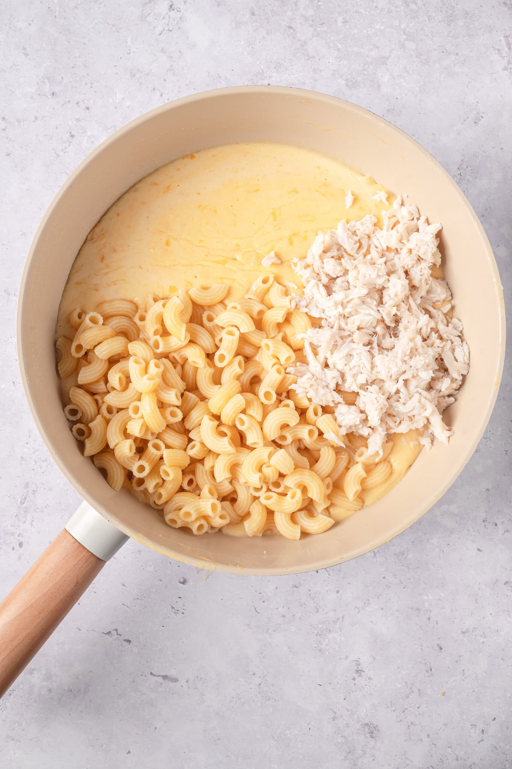 Creamy cheese and shredded chicken pasta in a skillet, ready to be baked.