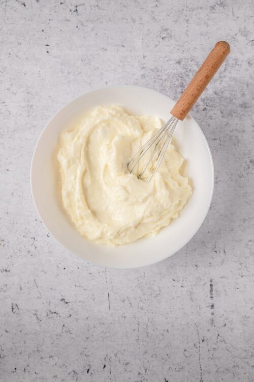 Creamy homemade mashed potatoes in a white bowl with a whisk, perfect for comfort food recipes.
