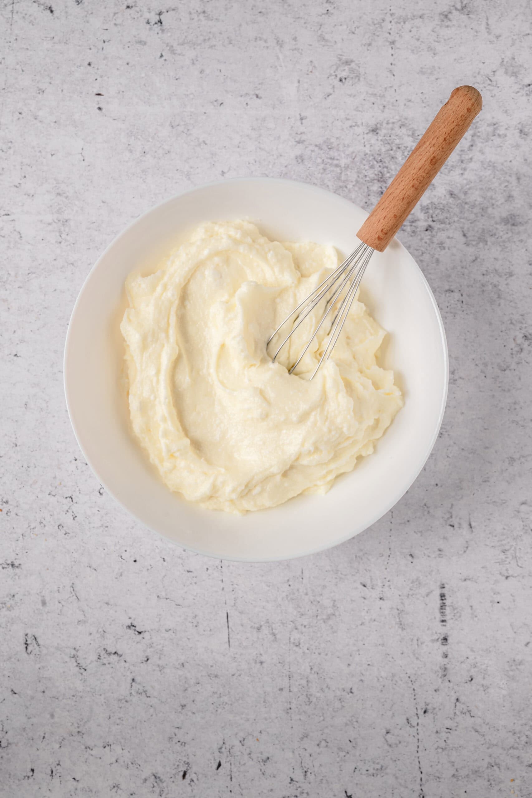 Creamy homemade mashed potatoes in a white bowl with a whisk, perfect for comfort food recipes.