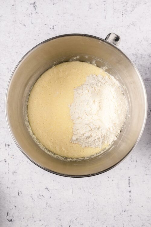 Light yellow cake batter with flour in a stand mixer bowl.