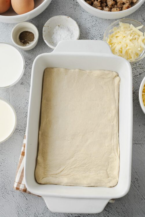 Thinly rolled pizza dough in baking dish ready for toppings.