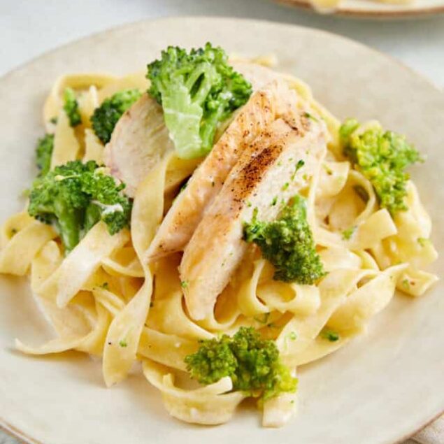 Creamy chicken and broccoli fettuccine pasta dish on a white plate.