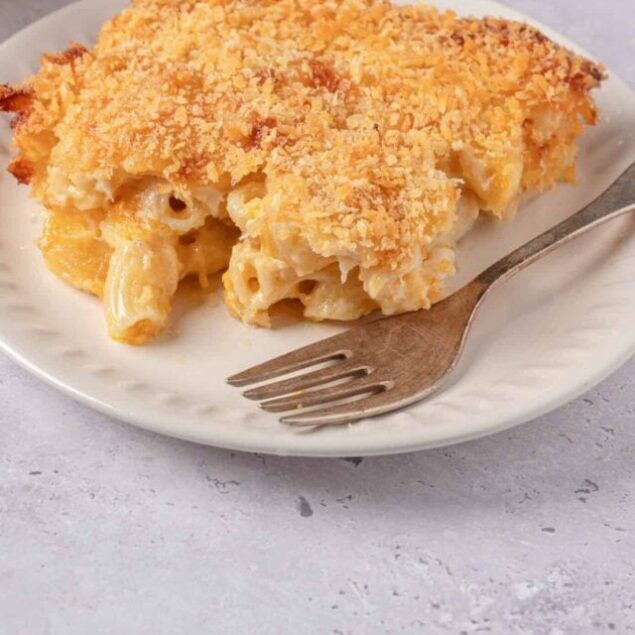 Creamy mac and cheese casserole with a crispy breadcrumb topping on a white plate.