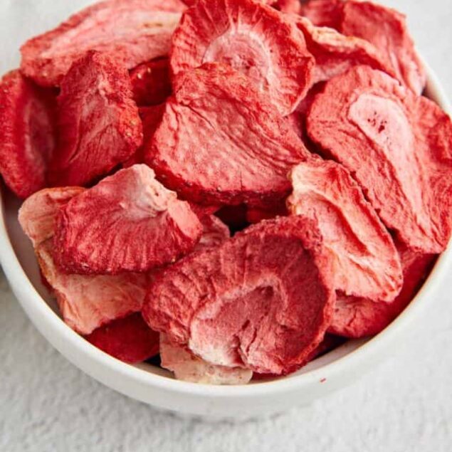 Dried strawberry slices in a white bowl, perfect for baking and snacking.