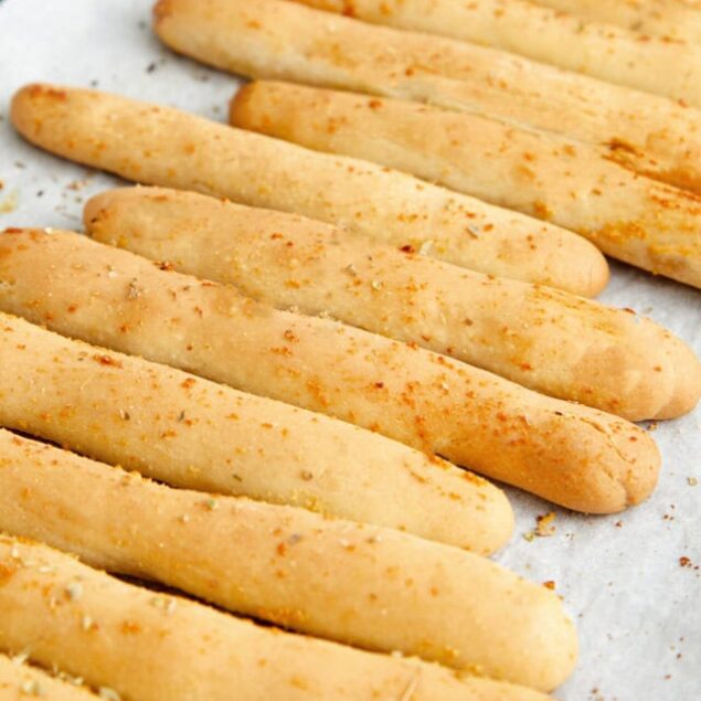 Golden Parmesan breadsticks on parchment paper.