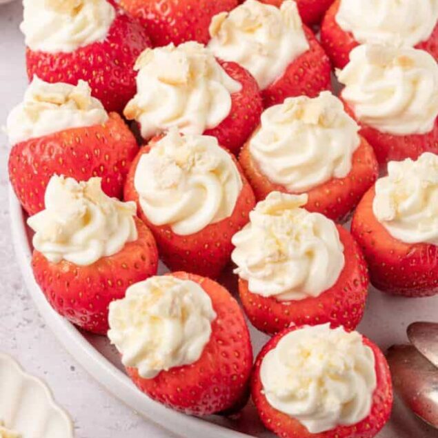 Fresh strawberries filled with whipped cream on a white platter, perfect for summer dessert recipes.