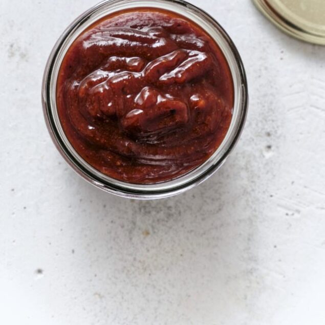 Sweet homemade barbecue sauce in a glass jar with a metal lid.