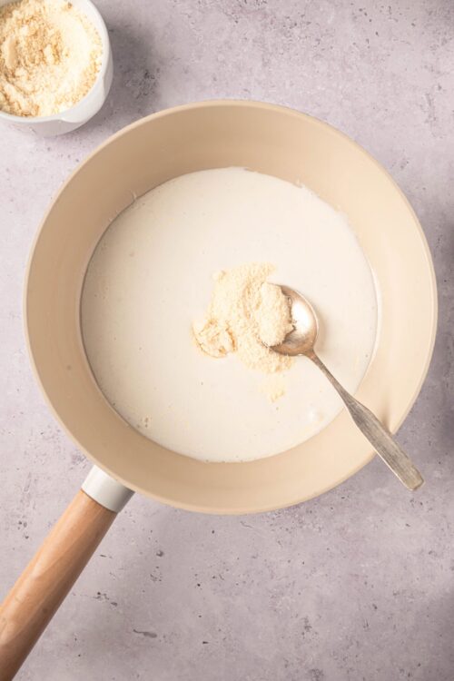 Creamy mixture with grated cheese in a beige mixing bowl.