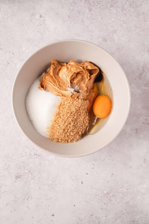 Creamy peanut butter, brown sugar, and egg in a mixing bowl, ready for baking or cooking.