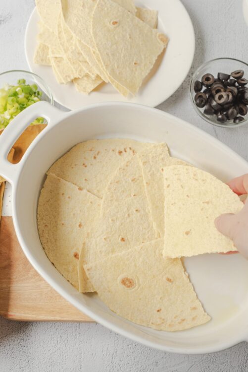 Shredded cheese being layered onto tortillas for homemade quesadillas.