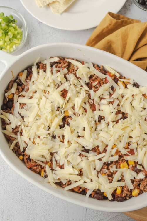 Cheeseburger casserole with ground beef, black beans, corn, and shredded cheese in baking dish.