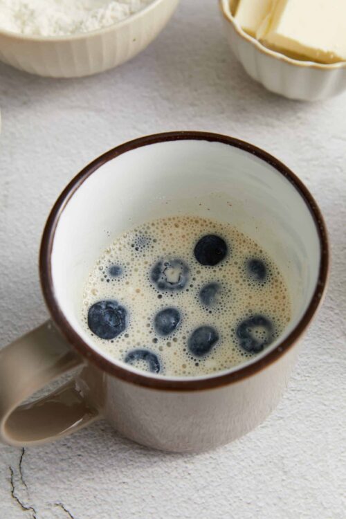 Fresh blueberries in a creamy mixture in a ceramic mug.