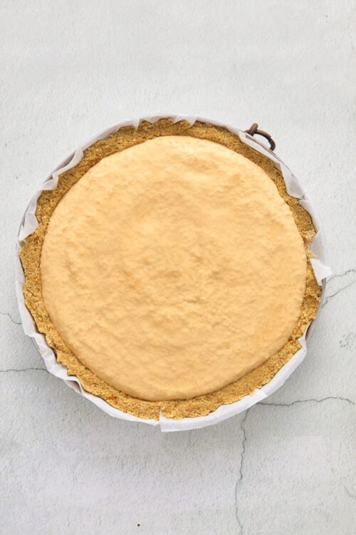 Cheesecake with graham cracker crust on white background.
