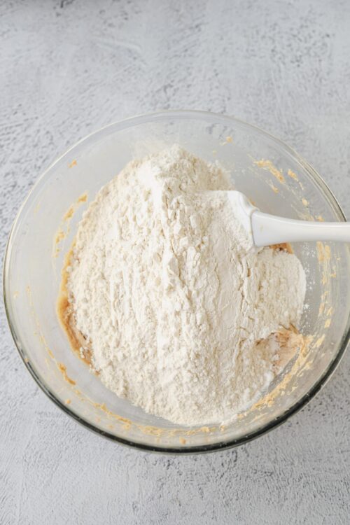 Flour being added to a mixing bowl for baking bread or pastries.